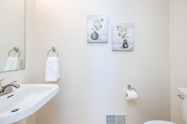 half bathroom with toilet, visible vents, and a sink