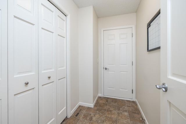 doorway featuring a textured ceiling and baseboards