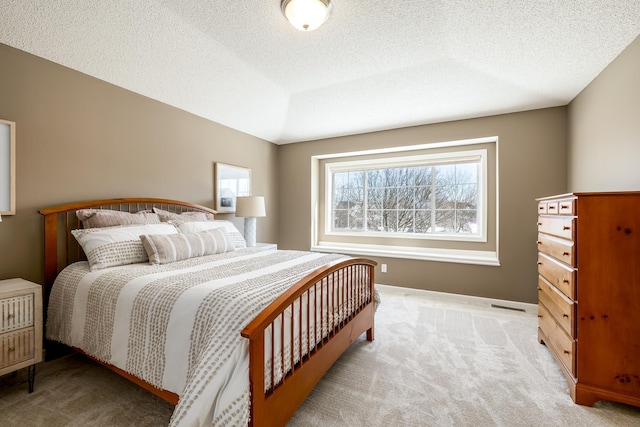 bedroom with light colored carpet and a textured ceiling