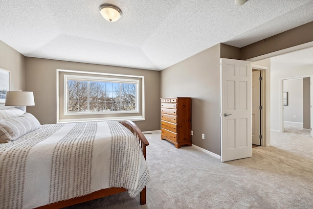 bedroom featuring light carpet, a textured ceiling, and baseboards