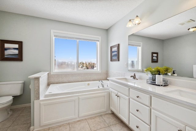 bathroom with a textured ceiling, toilet, a garden tub, and a sink