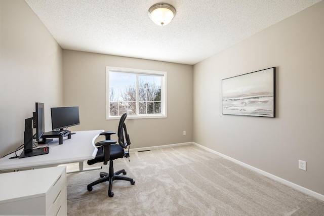 office area with light colored carpet, baseboards, and a textured ceiling