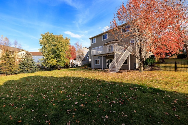 rear view of property with stairway, a yard, a wooden deck, and fence