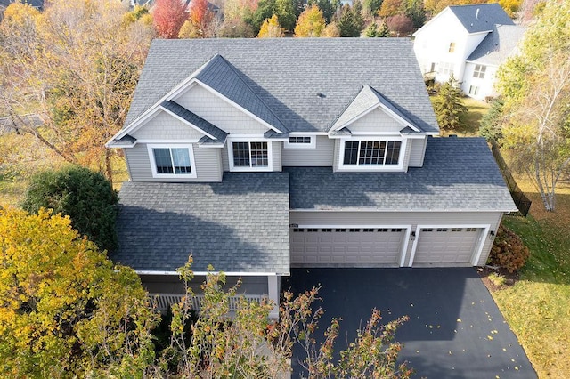 view of front of property featuring an attached garage, driveway, and a shingled roof