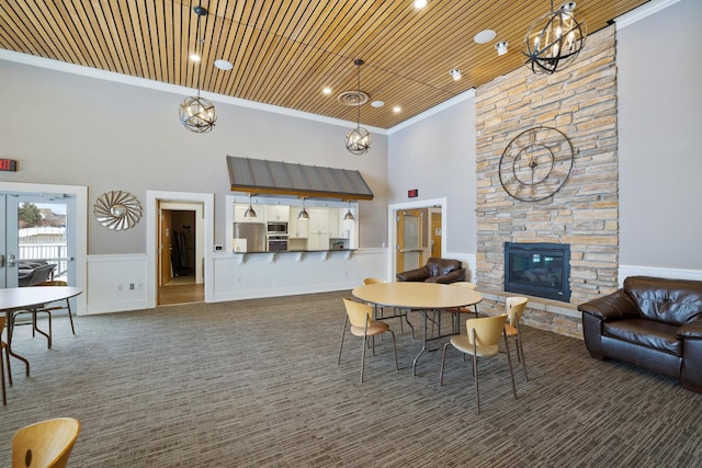 living room featuring wood ceiling, a towering ceiling, a fireplace, and crown molding