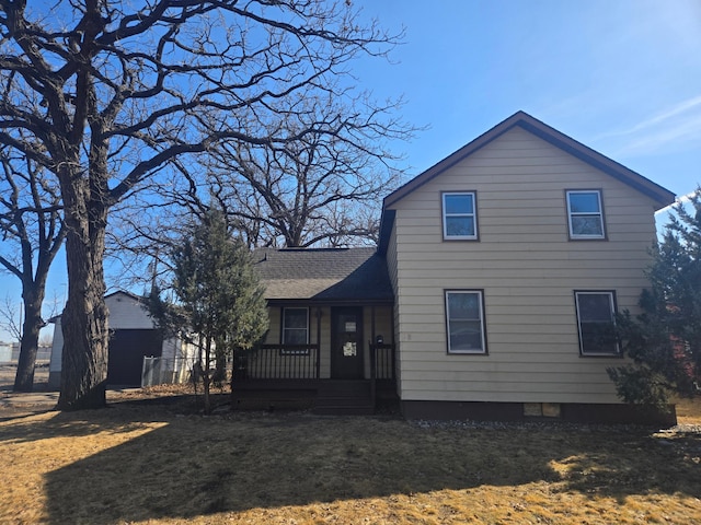 rear view of house featuring a yard, a porch, and a shingled roof