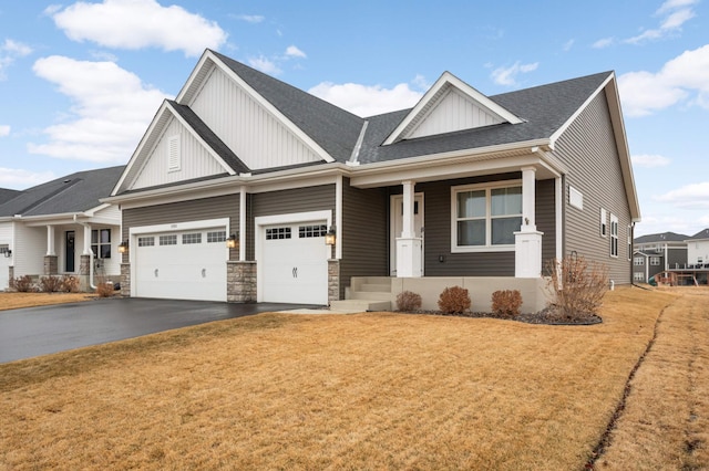 craftsman house featuring a front lawn, aphalt driveway, a porch, board and batten siding, and a garage