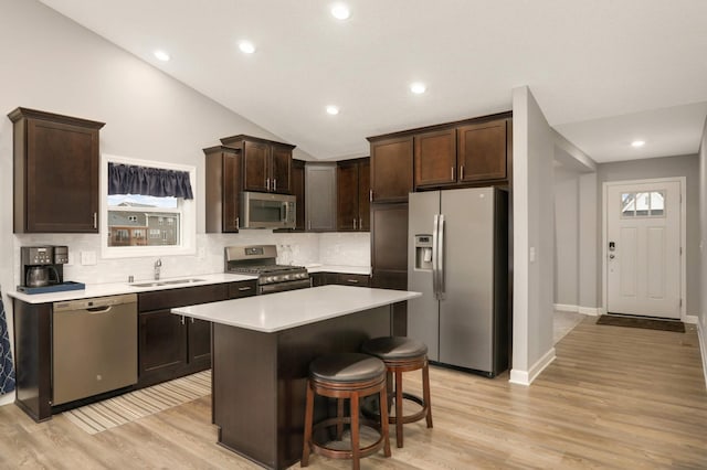 kitchen featuring light wood finished floors, a sink, stainless steel appliances, light countertops, and dark brown cabinets