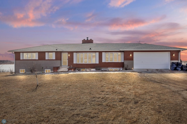 ranch-style house featuring a front yard, driveway, entry steps, a garage, and brick siding