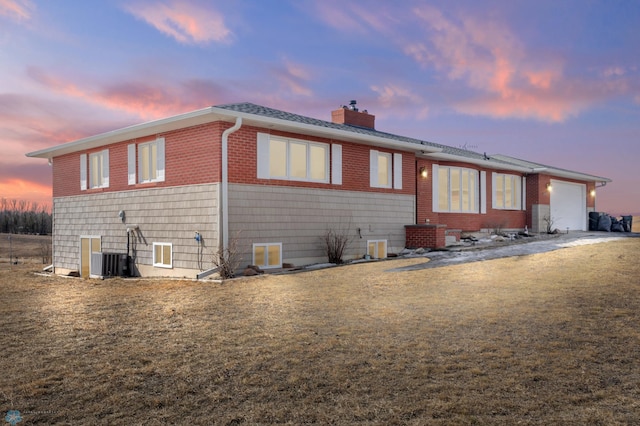 view of front of house featuring a garage, central AC unit, and a chimney