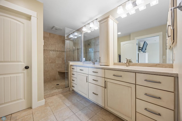 full bath featuring a sink, tiled shower, double vanity, and tile patterned flooring