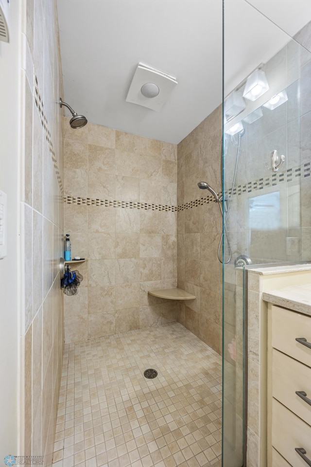 bathroom with tiled shower and vanity