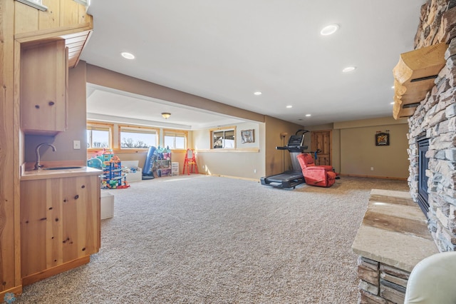 playroom with a sink, a stone fireplace, recessed lighting, and carpet flooring