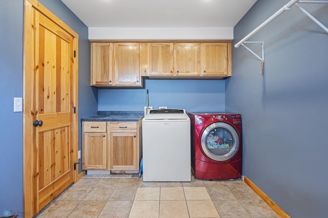 clothes washing area featuring washing machine and dryer, cabinet space, and baseboards