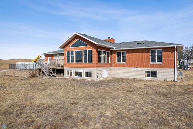 back of property featuring stairway, a shingled roof, a wooden deck, brick siding, and a chimney