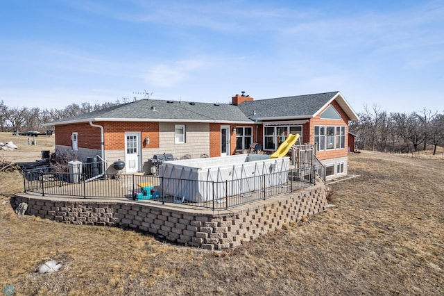 rear view of property with a shingled roof, a patio, a pool, and a chimney