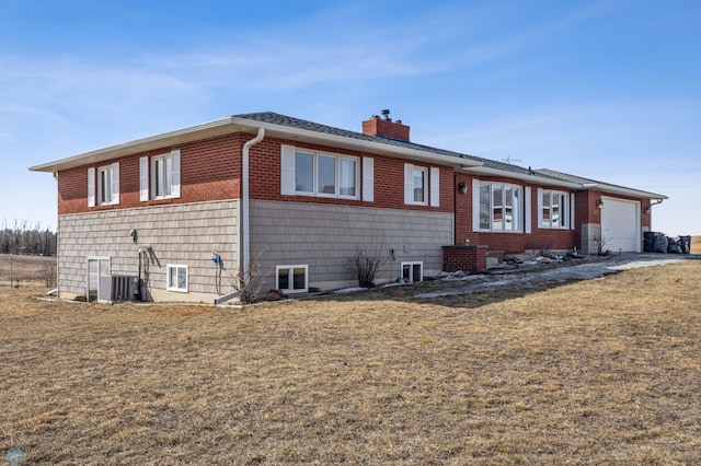 view of front of property featuring a chimney, brick siding, central air condition unit, and a garage