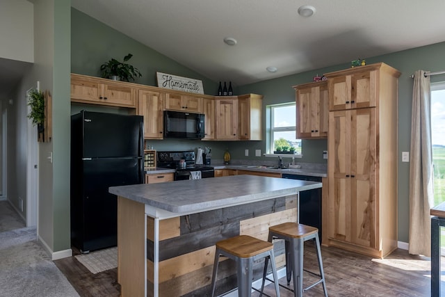 kitchen with a center island, dark wood finished floors, lofted ceiling, black appliances, and a sink