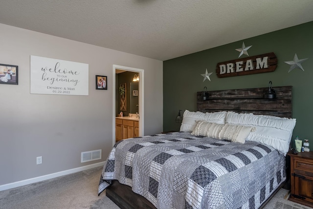 bedroom with visible vents, baseboards, carpet floors, ensuite bathroom, and a textured ceiling