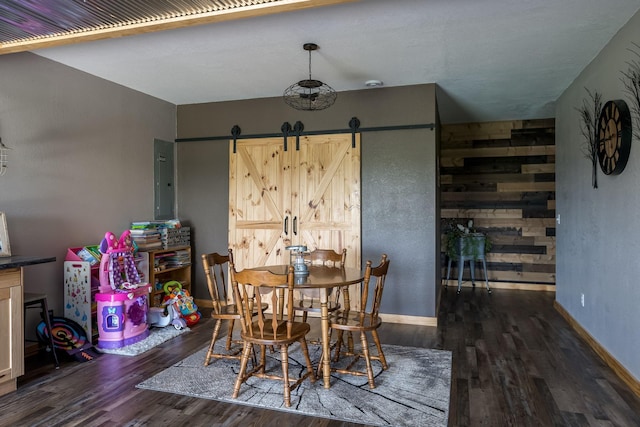 dining room featuring a barn door, wood finished floors, and baseboards