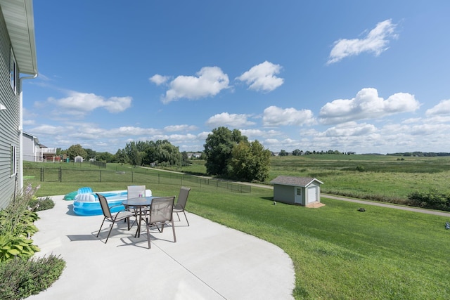 view of patio with an outbuilding, a fenced backyard, a storage shed, a rural view, and outdoor dining area