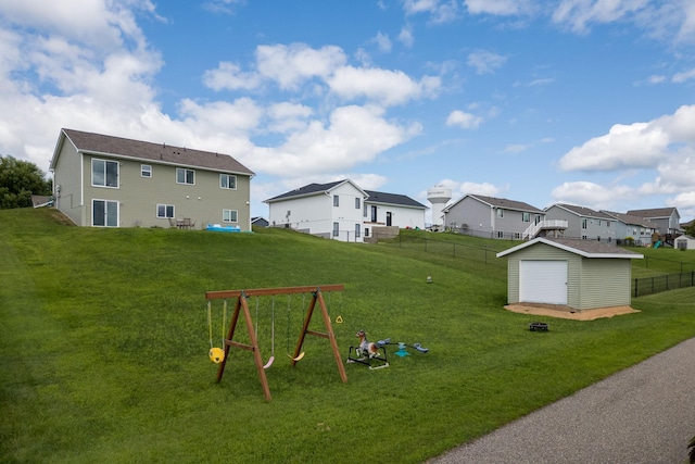 view of yard featuring an outbuilding, fence, a storage shed, a playground, and a residential view