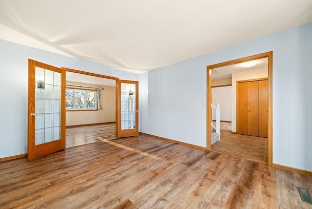 spare room featuring visible vents, french doors, baseboards, and wood finished floors