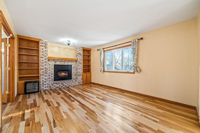 unfurnished living room featuring heating unit, a fireplace, baseboards, and wood finished floors