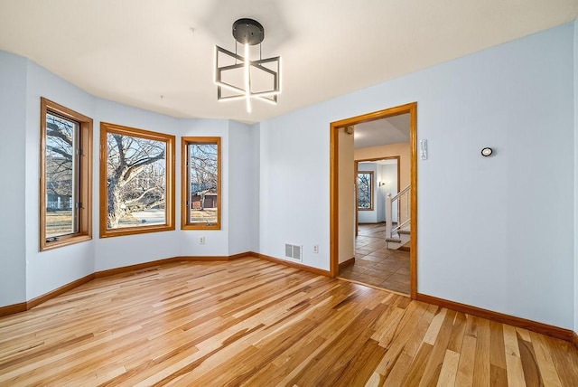 unfurnished dining area featuring stairs, light wood-style flooring, baseboards, and visible vents