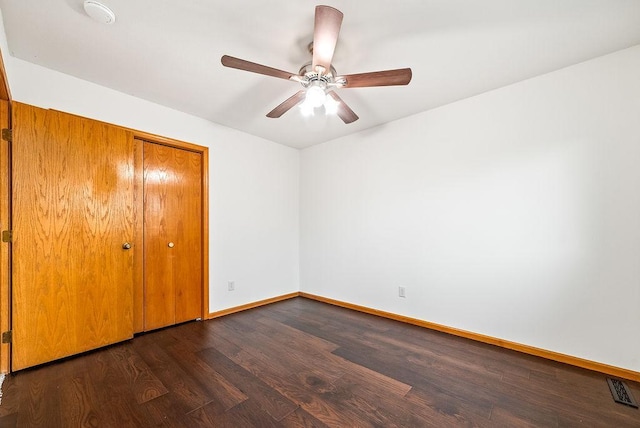 unfurnished bedroom with visible vents, baseboards, a closet, dark wood-style floors, and a ceiling fan