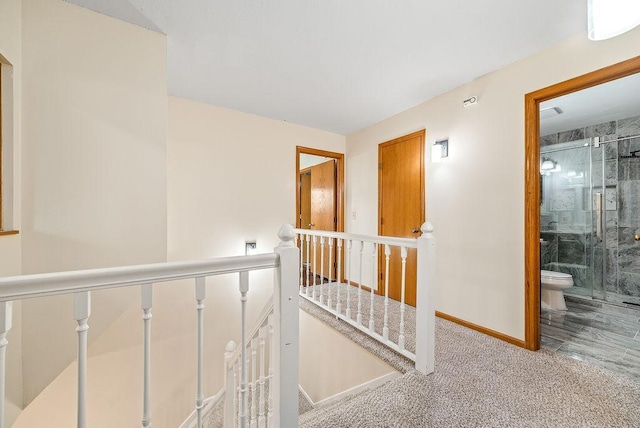 hallway with an upstairs landing, carpet, and baseboards