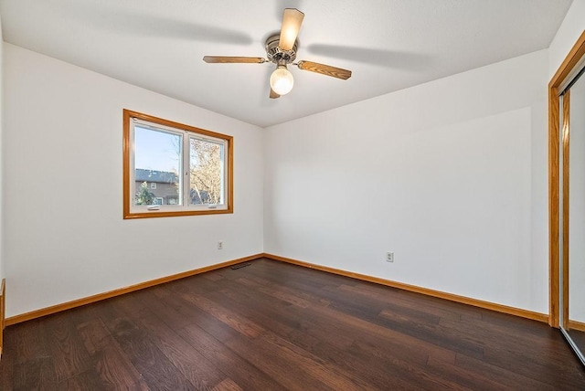 spare room featuring visible vents, a ceiling fan, baseboards, and dark wood-style flooring