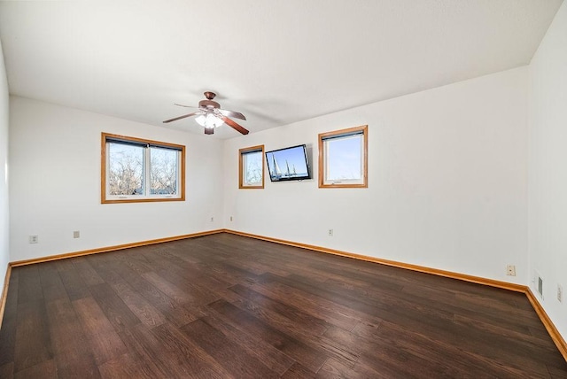 unfurnished room with visible vents, baseboards, dark wood-type flooring, and a ceiling fan