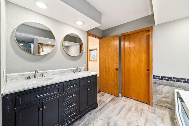 bathroom with a sink, tile walls, recessed lighting, and double vanity