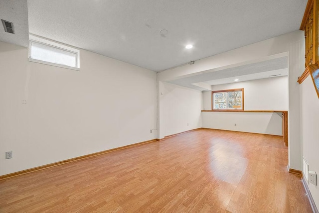 basement featuring plenty of natural light, baseboards, visible vents, and light wood-type flooring