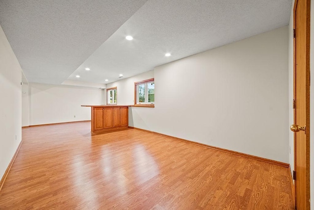 unfurnished room featuring light wood-style flooring, recessed lighting, baseboards, and a textured ceiling