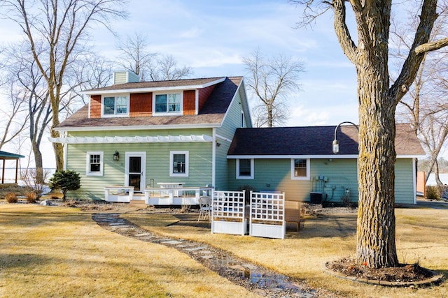 back of property featuring a yard, a deck, and a chimney