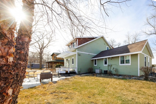 back of house featuring a lawn and roof with shingles