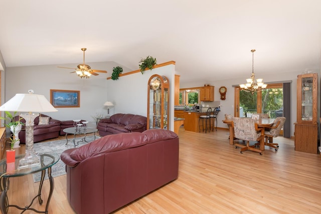 living room featuring lofted ceiling, ceiling fan with notable chandelier, and light wood-type flooring