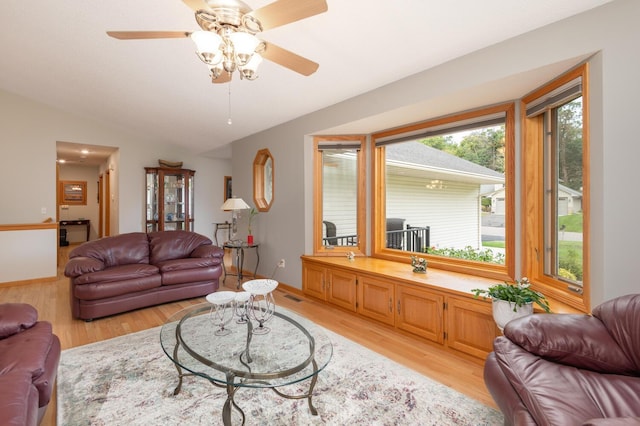 living room with visible vents, lofted ceiling, baseboards, and light wood finished floors