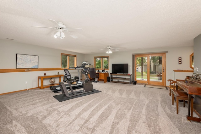 workout room with a textured ceiling, carpet, baseboards, and ceiling fan