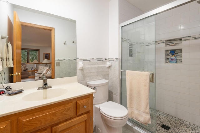 bathroom featuring tile walls, a stall shower, toilet, and vanity