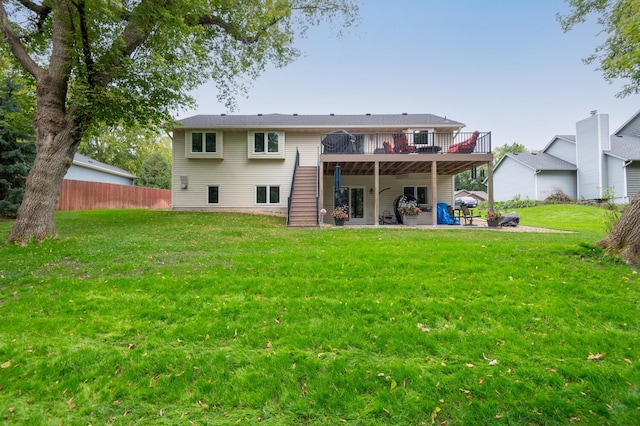 back of property with a deck, a patio, a lawn, and fence