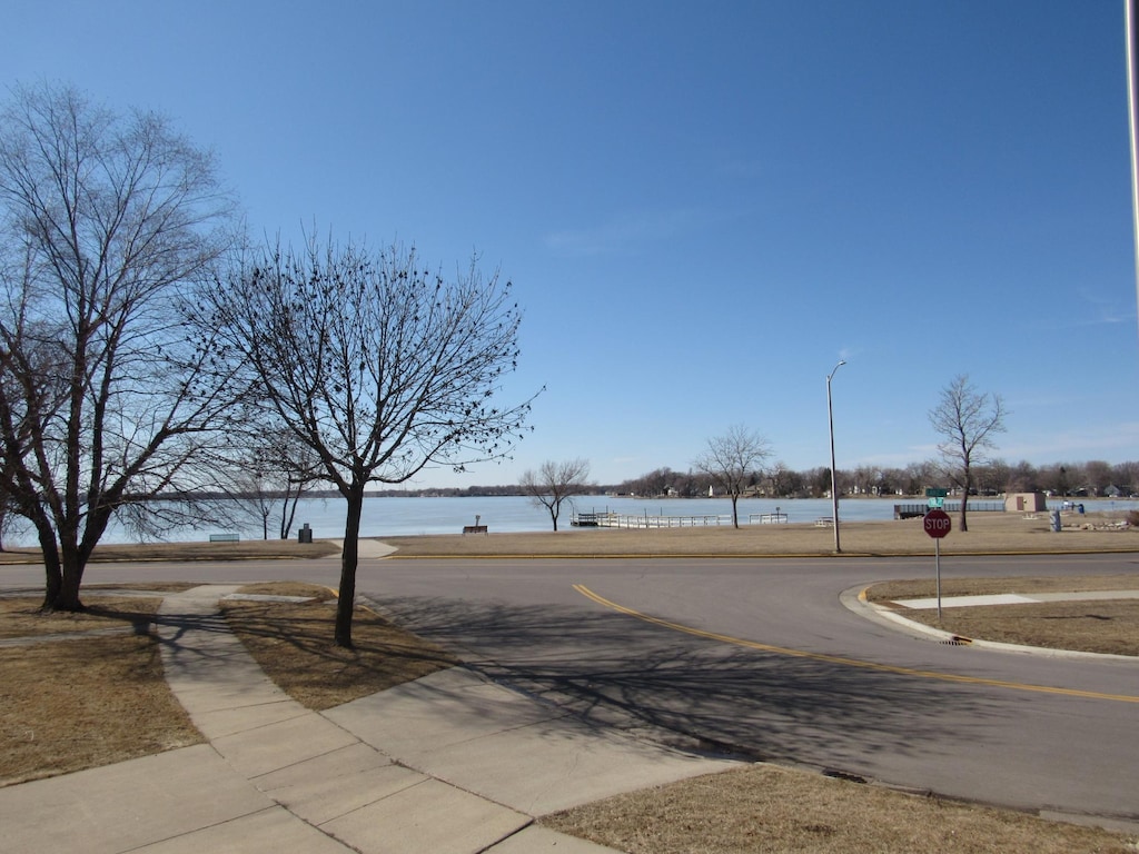 view of street featuring street lights, sidewalks, traffic signs, and a water view