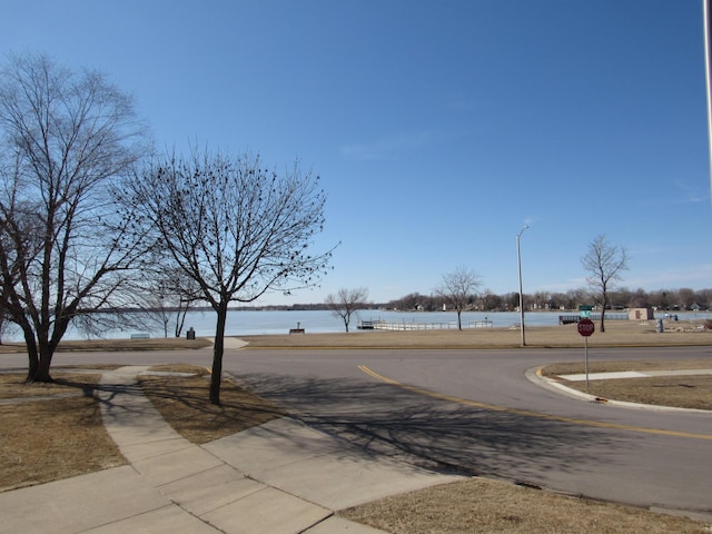 view of street featuring street lights, sidewalks, traffic signs, and a water view