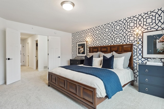 bedroom featuring light colored carpet, wallpapered walls, an accent wall, and baseboards