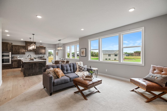 living room featuring a chandelier, recessed lighting, light colored carpet, and baseboards