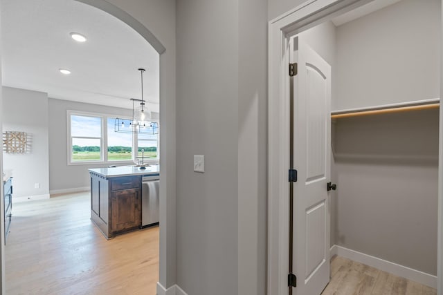 hall featuring arched walkways, recessed lighting, baseboards, and light wood-style floors