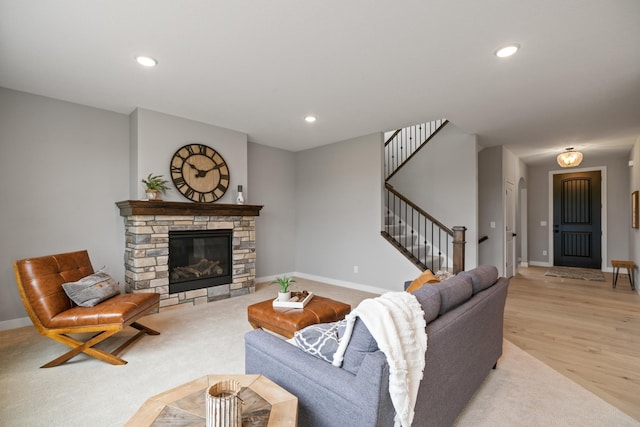 living room featuring baseboards, recessed lighting, a fireplace, stairs, and light wood-style floors