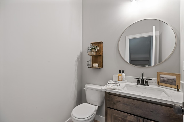 half bathroom with baseboards, toilet, and vanity